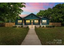 Charming craftsman home with a welcoming porch and lush green lawn at twilight at 6034 Tuckaseegee Rd, Charlotte, NC 28208
