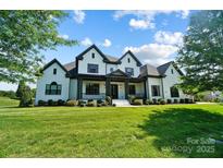 Stunning white home with black trim, covered porch, and meticulously manicured lawn at 1005 Grand Oak Dr, Waxhaw, NC 28173