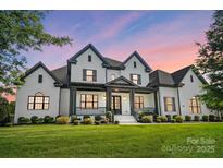 Stunning two-story white brick home with a covered front porch and beautiful landscaping at 1005 Grand Oak Dr, Waxhaw, NC 28173