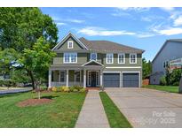 Charming two-story home featuring a covered front porch, attached two-car garage, and well-manicured lawn at 1012 Sudbury Ln, Matthews, NC 28104