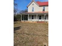 Two-story home featuring a red roof and a welcoming porch with brick base, perfect for enjoying the outdoors at 105 E Second Ave, Mount Gilead, NC 27306