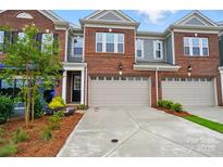 Beautiful brick townhome featuring a two-car garage, manicured landscaping, and a modern design at 12032 Lavinia Ln, Charlotte, NC 28277