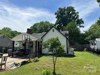 View of the home's backyard showcasing a small tree, air conditioning units, a basketball hoop, and patio area at 1212 Meadow Ln, Charlotte, NC 28205