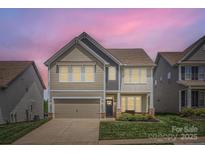 Charming two-story home with neutral siding, stone accents, and a manicured lawn with twilight sky at 128 Championship Dr, Mooresville, NC 28115