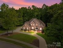 Beautiful brick home at dusk with lush landscaping, circular drive, and well-lit entrance for a welcoming appeal at 130 Churchill Dr, Salisbury, NC 28144