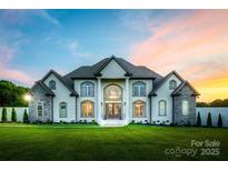 Stunning white brick home featuring a manicured green lawn and architectural details and a beautiful dusk sky at 1351 Highway 324 None, Rock Hill, SC 29730