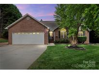 Charming brick home with a well-manicured lawn, two-car garage, and inviting front entrance at dusk at 2315 Perry Rd, Denver, NC 28037
