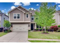 Charming two-story home featuring a two-car garage, manicured lawn, and beautifully landscaped front yard at 724 Lagan Ct, Fort Mill, SC 29715