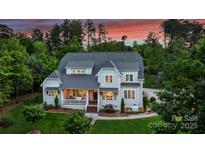 Stately two-story home featuring a covered front porch and lush landscaping against a backdrop of mature trees at 106 Thunder Hill Rd, Mooresville, NC 28117