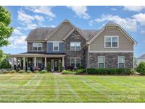 Impressive two-story home with a stone facade, well-manicured lawn, and inviting front porch at 1098 Matchstick Sw Pl, Concord, NC 28025