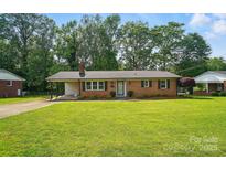 Charming brick home featuring a well-maintained lawn and covered carport at 137 Burton Hills Cir, Gastonia, NC 28054