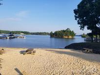 Scenic lake view featuring a sandy beach area with picnic tables, marina, and calm waters at 13932 Queens Harbor Rd, Charlotte, NC 28278