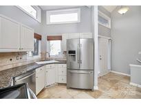 Bright kitchen featuring stainless steel appliances, light cabinetry, and travertine flooring at 13932 Queens Harbor Rd, Charlotte, NC 28278