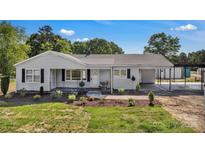 Charming single-story home featuring classic siding, black shutters, a covered porch and attached carport at 159 Old Home Pl, China Grove, NC 28023