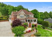 Stunning multi-story home with beautiful landscaping, a brick facade, covered porch and attached garage at 6164 Dwayne Starnes Dr, Hickory, NC 28602