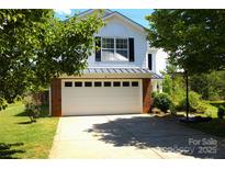 Attached two-car garage with a white door and brick accents, complemented by a well-maintained lawn at 6614 Wicked Oak Ln, Charlotte, NC 28216