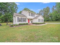 Charming two-story home featuring a bright red door and lush landscaping at 6910 Birdsong Ln, Waxhaw, NC 28173