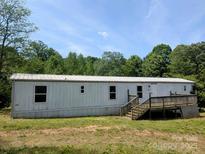 Exterior view of a single-story home featuring a wooden deck, modest landscaping, and a clean white exterior at 874 Old Home Place Way, Lincolnton, NC 28092