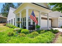 Charming home featuring a covered front porch with an American flag and well-manicured landscaping at 9003 Smokey Hill Ln, Fort Mill, SC 29707