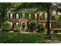 Charming two-story brick home with a well-manicured lawn and mature trees at 1261 Hawthorne Dr, Indian Trail, NC 28079
