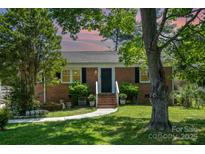 Charming brick home with a manicured lawn and mature trees at sunset at 145 Driftwood Dr, Mooresville, NC 28117