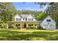 Charming two-story white home features a welcoming front porch and lush landscaping at 1956 Forest Ridge Dr, Stanley, NC 28164