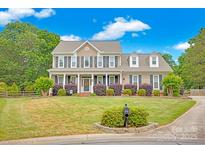 Charming two-story home with a manicured lawn, front porch, beautiful shrubbery, and classic architectural details at 3864 Meadow Ridge Nw Dr, Concord, NC 28027