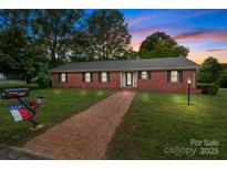 Charming brick home with well-maintained lawn, brick pathway, and a mailbox decorated with a North Carolina flag at 402 School St, Rockwell, NC 28138