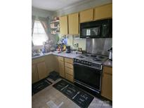 Functional kitchen features wooden cabinets, black microwave, and an electric stovetop oven range at 515 Benton St, Monroe, NC 28110