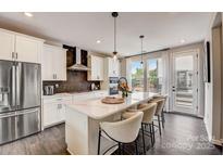 Modern kitchen with stainless steel appliances, an island with seating, and lots of natural light at 739 Hoke Ln, Davidson, NC 28036