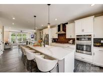 Modern kitchen features a large island with seating, white cabinets, stainless steel appliances, and open layout to living area at 747 Hoke Ln, Davidson, NC 28036
