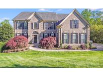 Beautiful brick home featuring manicured lawn, lush landscaping and black shutters at 9433 Stonebridge Way, Mint Hill, NC 28227