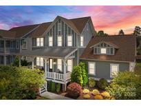 Charming two-story home with a welcoming front porch, lush landscaping, and beautiful sunset sky at 10822 Brandie Meadow Ln, Huntersville, NC 28078