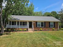 Charming one-story brick home features a covered porch and well-maintained landscaping at 1109 Reid Harkey Rd, Matthews, NC 28105