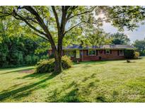 Well-maintained brick home featuring a lush, green lawn and mature trees providing shade at 211 Amos Homesley Rd, Cherryville, NC 28021