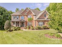 Charming two-story red brick home with lush landscaping and a welcoming front porch at 3304 Danhill Pl, Matthews, NC 28105
