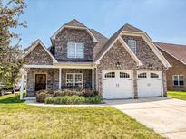 Charming brick home with a two-car garage and a well-manicured lawn on a sunny day at 4562 Lanstone Sw Ct, Concord, NC 28027