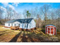 Charming one-story home with a wooden deck and a red storage shed nestled on a sprawling lot with mature trees at 4845 Midway Sand Rd, Hickory, NC 28601