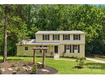Charming two-story home featuring a well-maintained lawn and lovely landscaping in a peaceful, wooded setting at 7016 Wannamaker Ln, Charlotte, NC 28226