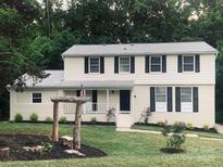 Charming two-story home with a well-manicured lawn, a front porch, and a decorative wooden structure in the front yard at 7016 Wannamaker Ln, Charlotte, NC 28226