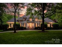 Elegant two-story brick home featuring a lush green lawn, mature trees, and inviting entrance with stately columns at 8305 Bar Harbor Ln, Charlotte, NC 28210