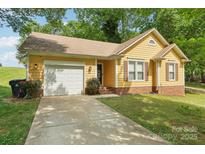 Charming yellow home with attached garage, brick accents, and well-maintained landscaping at 11701 Brockley Ct, Charlotte, NC 28215