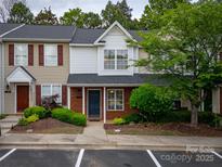 Charming townhouse featuring a brick facade, blue door, manicured landscaping, and red shutters at 118 Barnhardt Loop, Mooresville, NC 28117