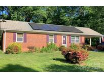 Charming brick home featuring solar panels, colorful shutters, a metal roof, and a well-maintained front yard at 1750 Sells Rd, Salisbury, NC 28144