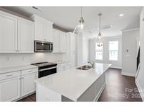 Bright kitchen features a center island, modern appliances, and white cabinetry against dark wood floors at 2013 Clarksdale Dr # 38, Charlotte, NC 28206