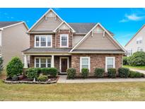 Charming two-story home with stone and wood facade, lush landscaping, and inviting front entrance at 282 Fischer Rd, Fort Mill, SC 29175