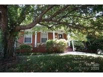 Charming brick home with a front porch, framed by mature tree with lots of shade and curb appeal at 5127 Murrayhill Rd, Charlotte, NC 28210