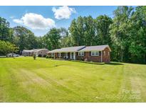 Charming single-story brick home with a lush green lawn and mature trees in a serene setting at 707 Hester Dr, Dallas, NC 28034