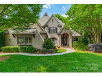 Charming brick home featuring a manicured lawn, mature trees, and elegant landscaping at 7138 Wessynton Dr, Charlotte, NC 28226