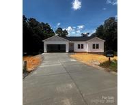 Charming white home with an attached garage and a long driveway nestled amongst mature trees at 3137 Riber Ln, Claremont, NC 28610